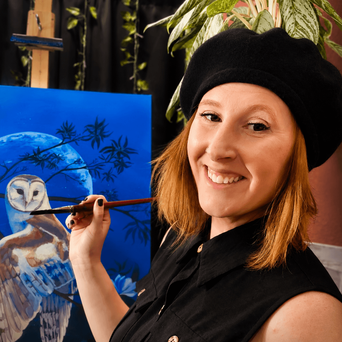 Eva Creature painting beside an owl artwork in her studio.